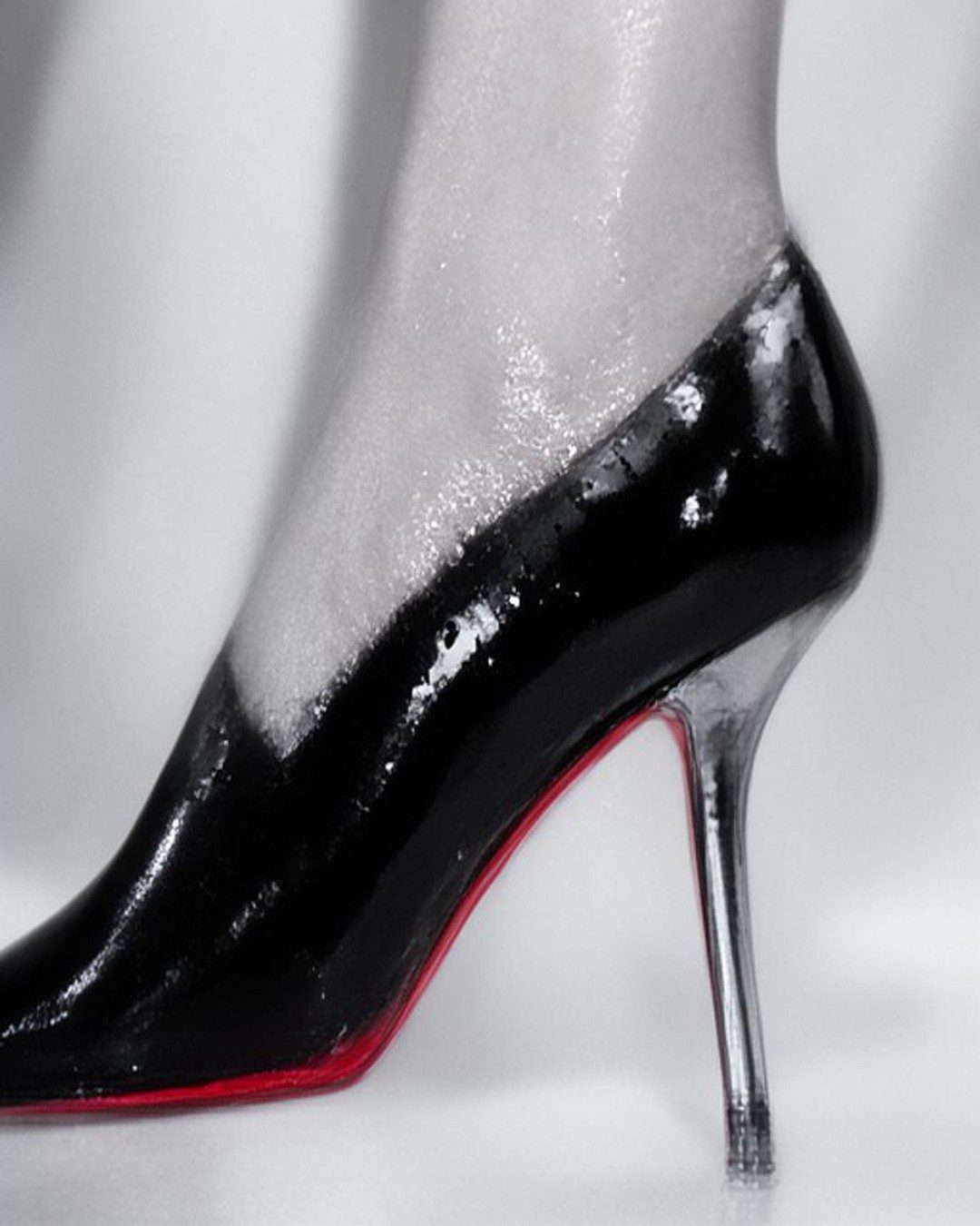 Close study of legs in glossy red heels against black